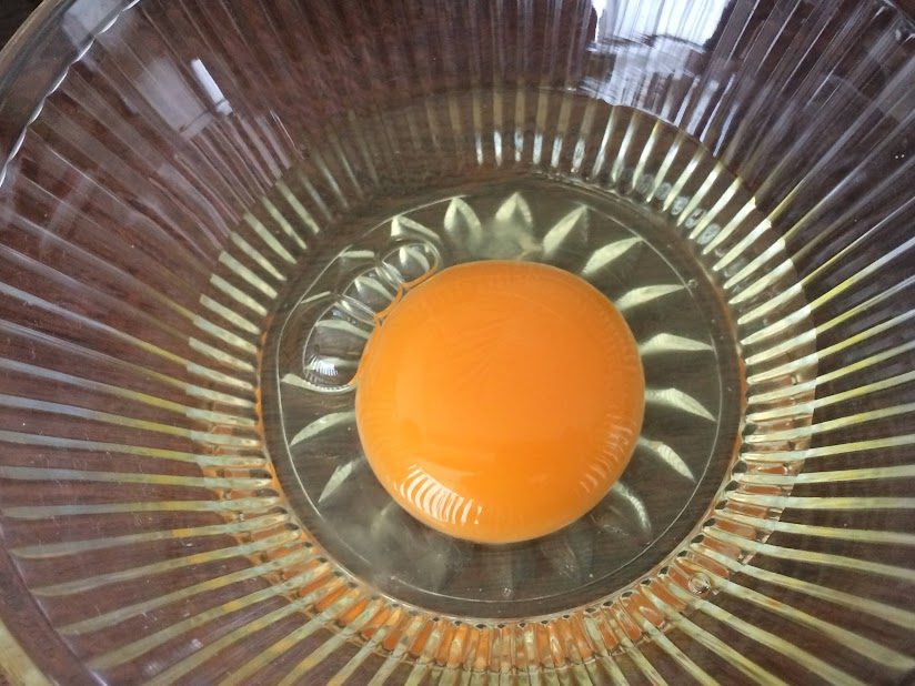 ガラス製搾り器に置かれた鮮やかなオレンジ色の卵黄