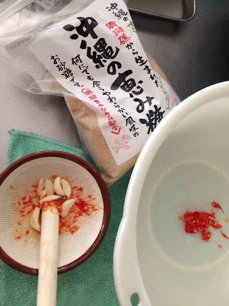 島唐辛子と島ニンニクをすり鉢で潰すソムタム下準備