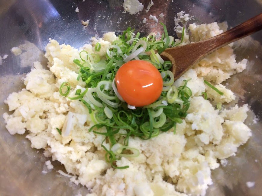 ボウルでじゃがいもに青ネギと卵黄を混ぜるコロッケの下ごしらえ