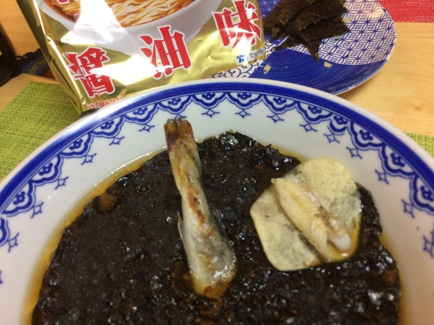 青白い器に盛られた黒いこまいラーメンとトッピング具材